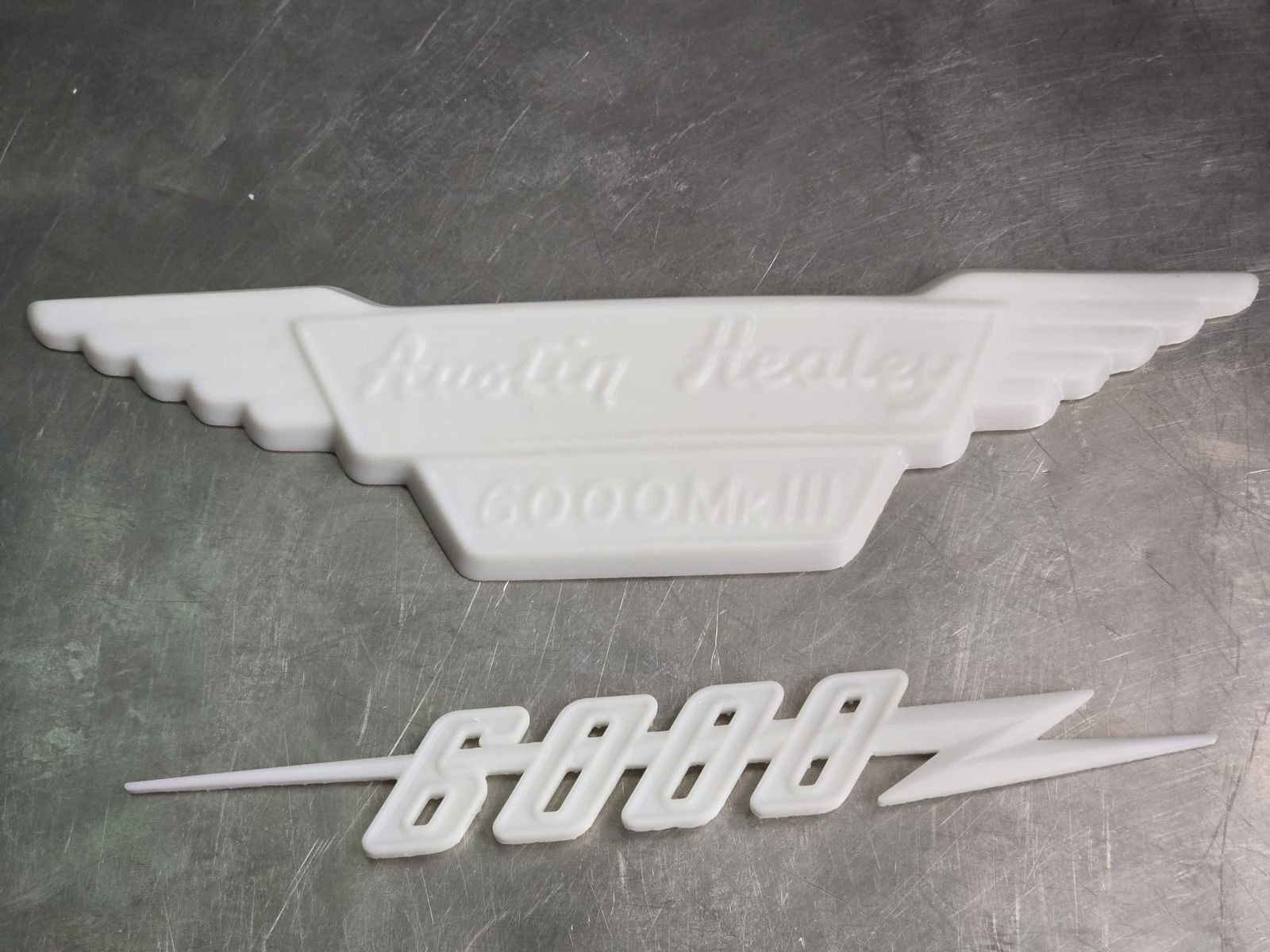 Zwei weiße gedruckte Emblem-Modelle mit Schriftzug
