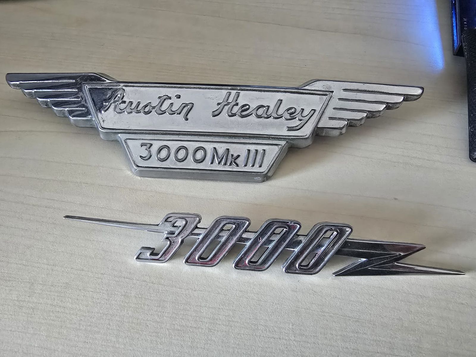 Zwei Original-Embleme eines Austin-Healey mit der Aufschrift 3000 und 3000 Mk III